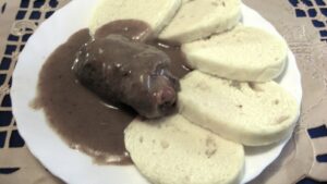 Brown gravy–covered sausage served with white bread slices on a plate.