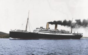 Old-fashioned ocean liner with a black hull and white superstructure, emitting dark smoke as it sails on calm blue water.