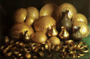 Pile of gold decorative vessels, bowls, and bracelets with dotted patterns arranged in a still life.**(informative, concise)**