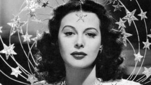 Black-and-white portrait of a glamorous woman with dark waves and star-shaped decorations surrounding her head.