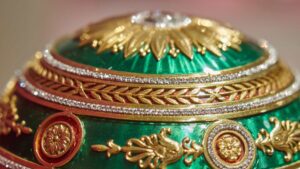 Close-up of an ornate gold and jewel-encrusted decorative piece on emerald green fabric.