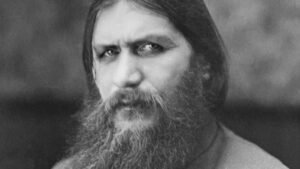 Close-up black-and-white portrait of a man with a long beard and solemn expression.